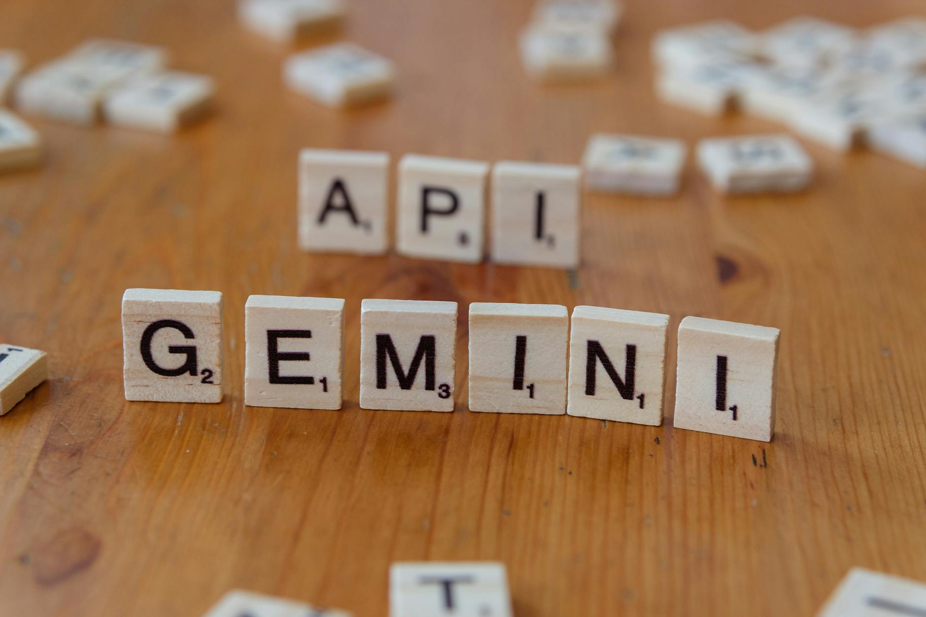 Płytki Scrabble układające się w słowa API i GEMINI na drewnianym blacie