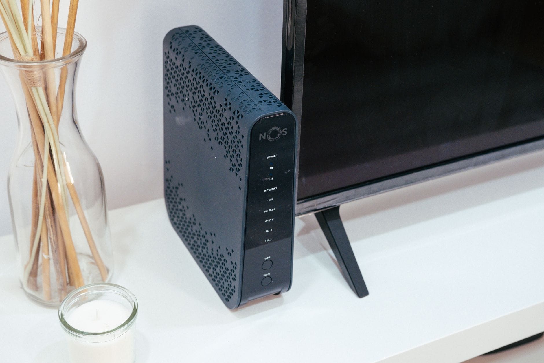 Nowoczesny router w salonie obok szklanej dekoracji i telewizora