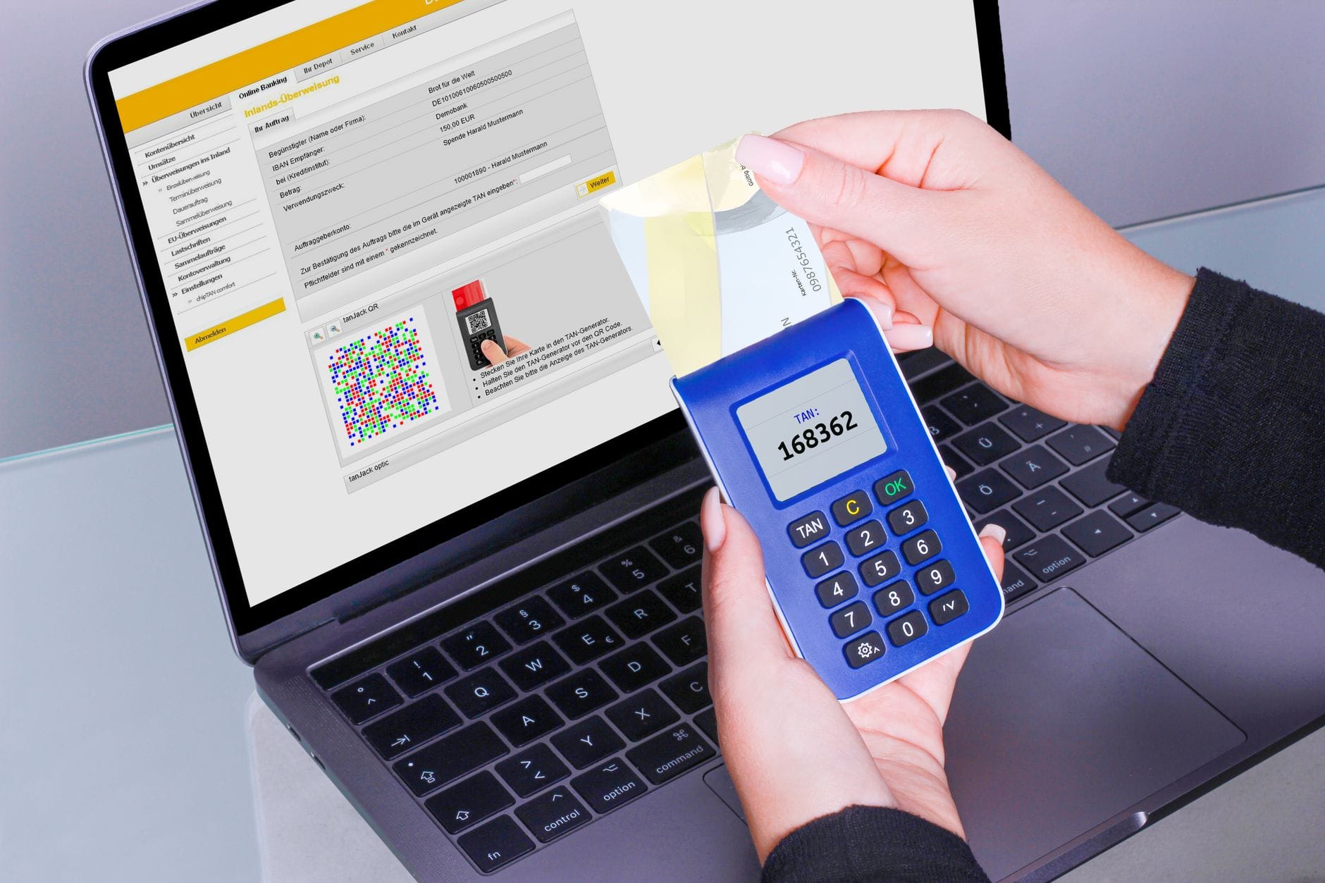 Dłoń korzystająca z generatora TAN obok laptopa podczas logowania online