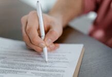 Dłoń podpisująca oficjalny dokument długopisem